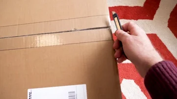 Man unboxing large cardboard box containing Italian DeLonghi convection heater Stock Footage 85911935