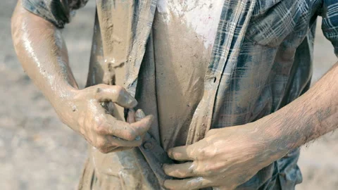 Man Unbuttoning checkered Shirt Smeared with Swamp Outdoors. Close up of Stock Footage 248058877