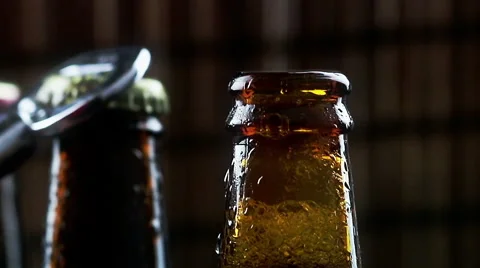 Man uncap three bottles of fresh beer with foam and drops on dark background 스톡 동영상 59791264