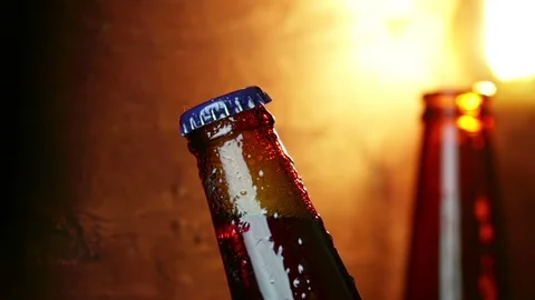 Man uncup a bottle of beer with foam with ice frozen drops, on gold brown Video stock 100342963
