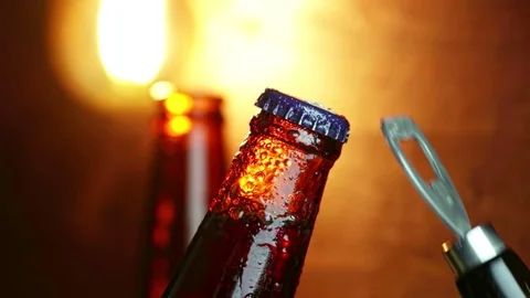 Man uncup a bottle of beer with foam with ice frozen drops, on gold brown Stock Footage 100343398