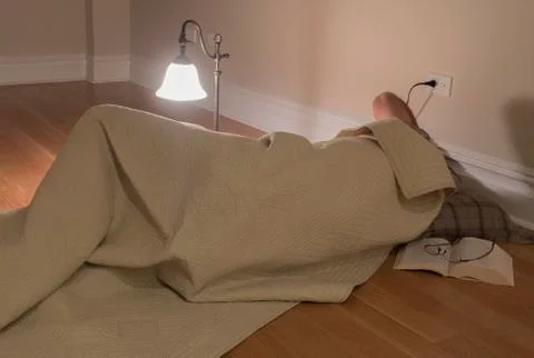 Man under blanket on floor Stock Photos