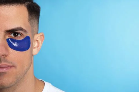 Man with under eye patch on light blue background. Space for text Stock Photos