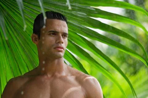 Man under giant leaf in rain shower Stock Photos