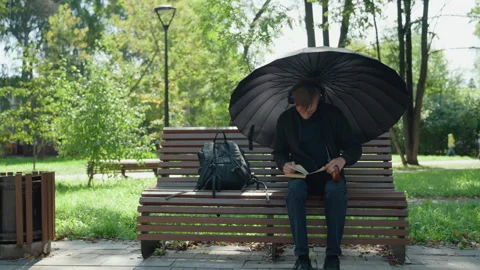 Man under umbrella practicing script, Individual practicing script in sunny city Видео 333655284