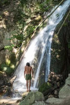 Man under a waterfall in the woods. Stock Photos