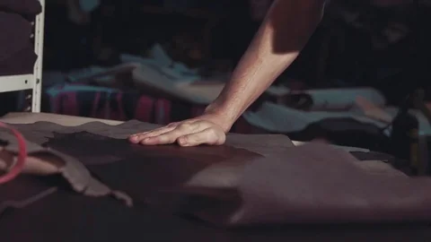 A man unfolds a roll of leather on a table Stock Footage 75700620