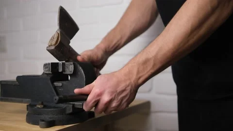 The man unhooked an old carving axe in a black vise with a screw handle, Close-u Stock Footage 149615818