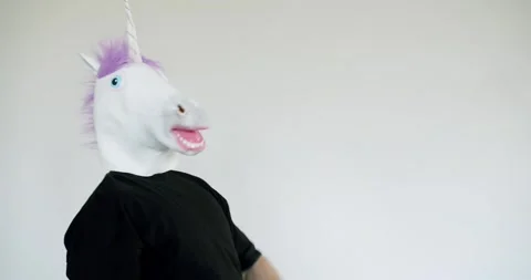 Man in Unicorn Mask Dances Playfully in Studio with White Background Stock Footage 344269634