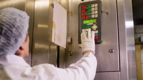 Man in uniform adjusts temperature on industrial refrigerator in factory. Stock Footage 250091028