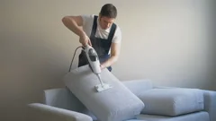 Man In Uniform Cleaning Fabric Of The Sofa With Dry Steam Cleaner Sofa With Dry Steam Cleaner