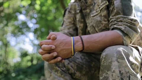 The man in uniform folded his hands. A soldier with a blue and yellow ribbon Stock Footage 265898401