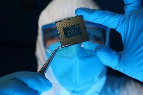 Man in uniform holds microprocessor with forceps Stockfoto's