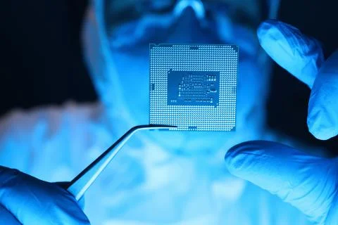 Man in uniform holds microprocessor with forceps 스톡 사진
