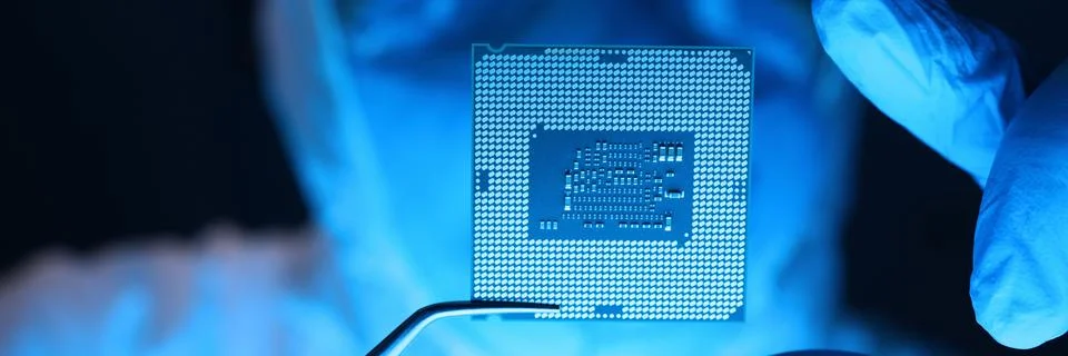 Man in uniform holds microprocessor with forceps 스톡 사진