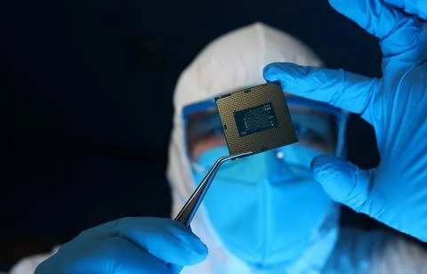 Man in uniform holds microprocessor with forceps Stockfoto's