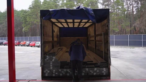 Man in uniform jacket loads PVC profile sheets into lorry trailer Video stock 304393305