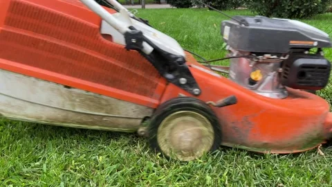 Man in uniform with orange lawn mower mows green grass Video stock 285250198