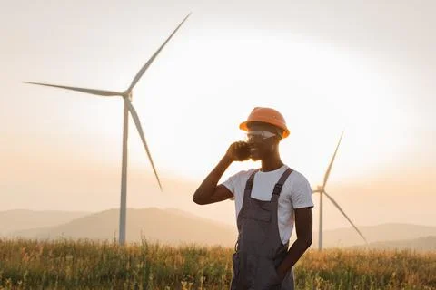 Man in uniform talking on mobile on farm with wind turbines Stock Photos