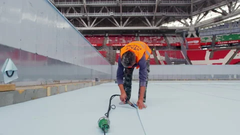 Man in uniform uses tool to process flooring for pool Stock Footage 230036578