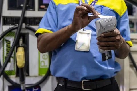 Man in uniform using portable card machine for fuel payment transaction Stock-Fotos