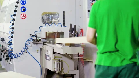 A man in a uniform works on a woodworking machine in a furniture factory. 4K Stock Footage 165239217
