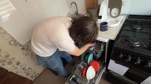 Man unloading clean dishes from dishwasher at home. Overhead view of kitchen Stock Footage 335645635