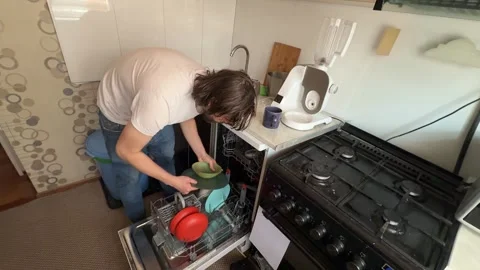 Man unloading clean dishes from dishwasher at home. Overhead view of kitchen Stock Footage 336980394