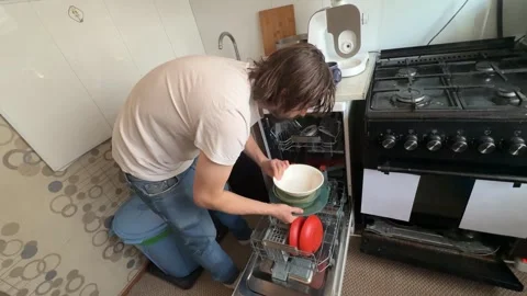 Man unloading clean dishes from dishwasher at home. Overhead view of kitchen Stock Footage 336980395