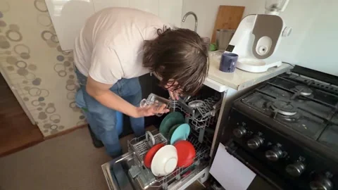 Man unloading clean dishes from dishwasher at home. Overhead view of kitchen Stock Footage 336980412