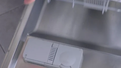 Man unloading dishwasher and taking out white utensil and cutlery from basket. Stock Footage 116375370
