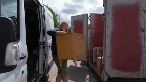 Man Unloading Old Cabinet from Van into Metal Waste Container Stockbeeldmateriaal 339159908