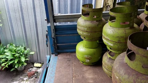 A man is unloading small green LPG gas cylinders Stock Footage 231883509