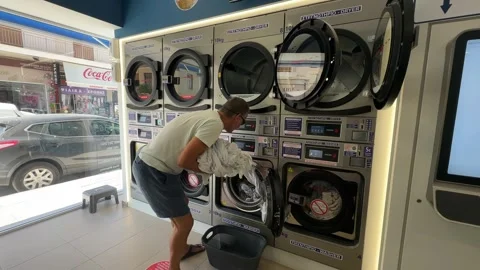 A man is unloading the washer and loading the dryer in a self service smart Video stock 328296385