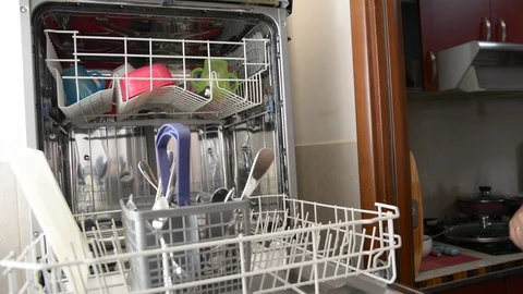 Man unloads clean dishes from the bottom basket of the dishwasher. Man doing Hou Vídeos de archivo 95656172