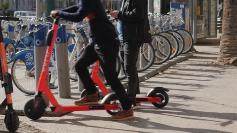 Man unlocking an electric shared scooter and taking off. Stock Footage 120734341