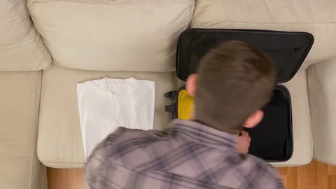 Man unpacking clothes from suitcase Stock Footage 74087054