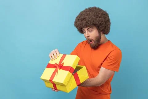 Man unpacking present, looking inside box with shocked and scared expression Foto stock
