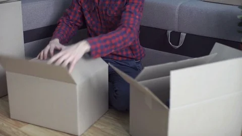 A man unpacks boxes after moving to a new apartment Stock Footage 83481453