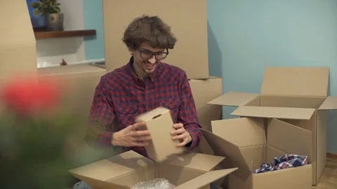 A man unpacks boxes after moving to a new apartment Stock Footage 83481787