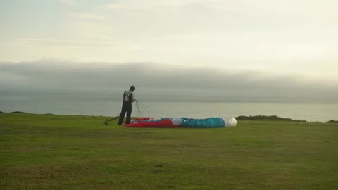 Man unravelling ropes of a paragliding canopy. Stock Footage 329608053