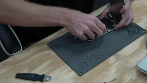 Man unscrewing and taking screen off Apple iPhone to repair and replace Stock Footage 166305254