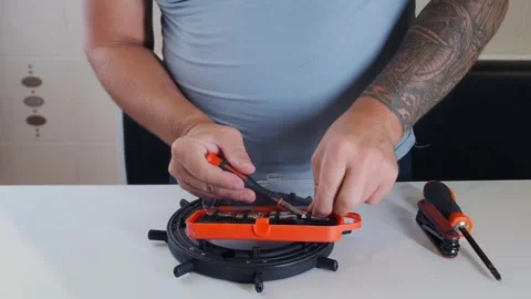 Man unscrewing bolt with screwdriver in close-up view, using interchangeable Stock Footage 333769181