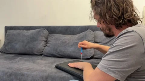 Man unscrewing laptop case with screwdriver, opening device for repair or Stock Footage 337110136