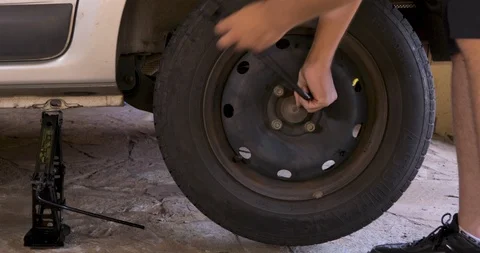 Man unscrewing nut to remove flat tire Stock Footage 126791984