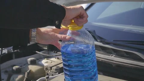 A man unscrews the cap of a bottle of windshield washer fluid Stock Footage 321174482