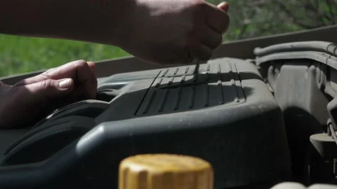 A man unscrews the nuts on the car engine with a key. Work under the hood of the Stock Footage 154893047