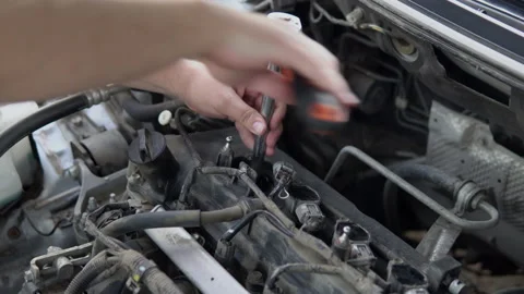 A man unscrews an old spark plug from a car engine with a tool Stock Footage 139158529