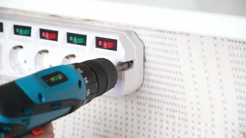 A man unscrews a screw with a screwdriver to remove socket adapter with switches Stock Footage 167929362
