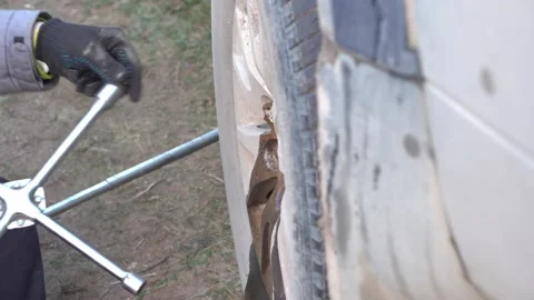 Man unscrews the wheel nuts for replacement with a wrench. Stock Footage 143575041